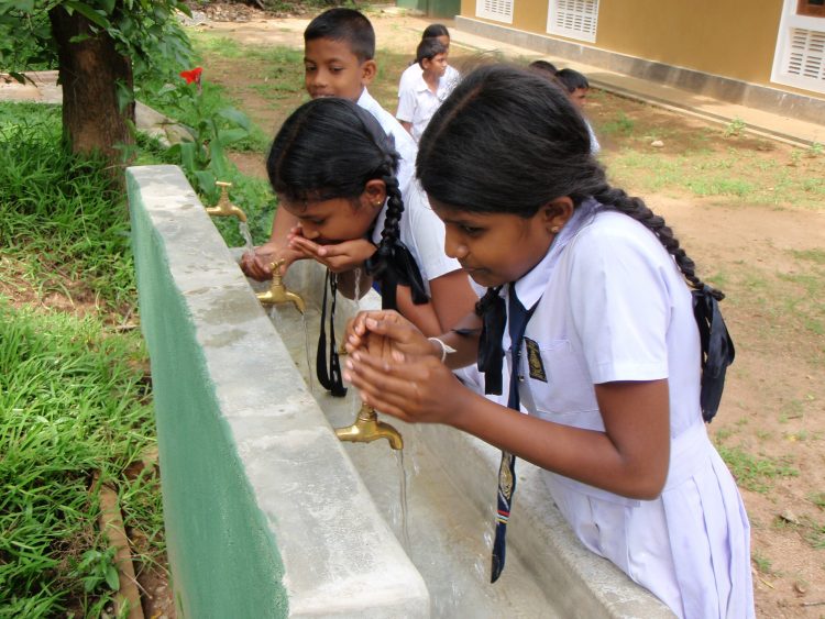 Twee meisjes drinken schoon drinkwater in Sri Lanka.