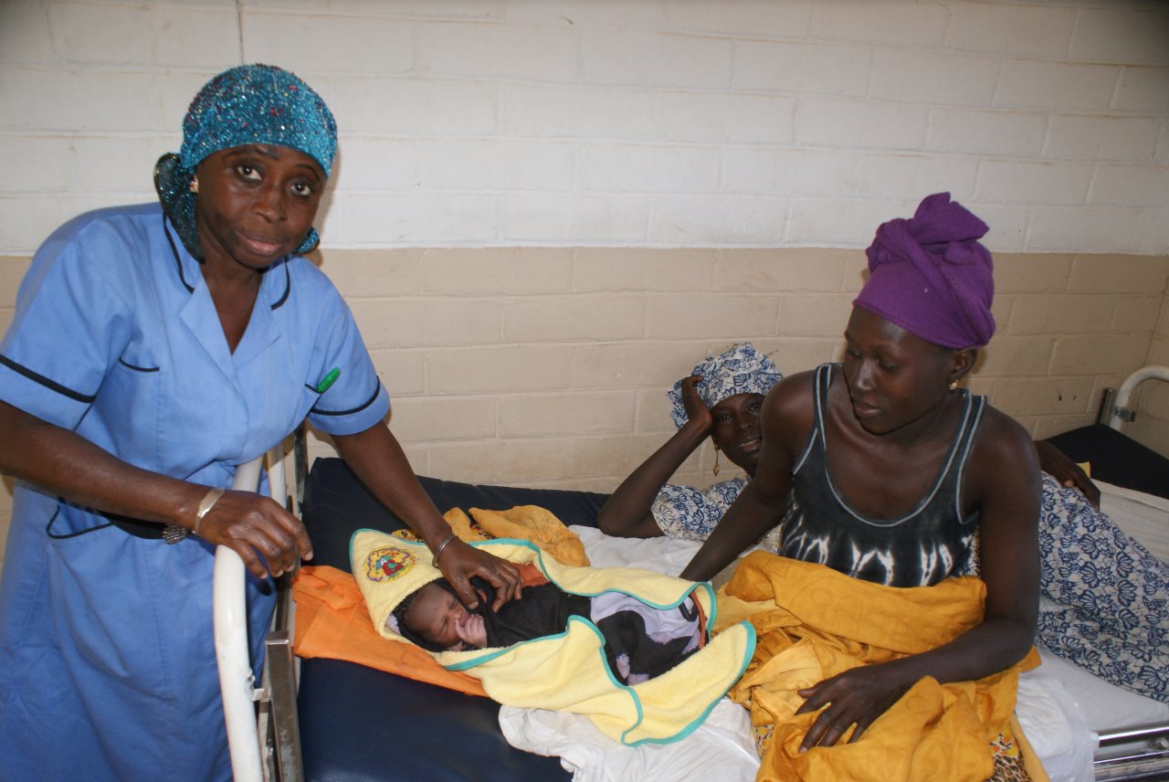 Drie vrouwen met een pasgeboren baby op bed in Gambia.