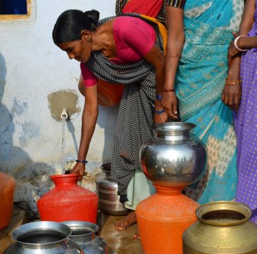 Een vrouw tapt schoon drinkwater in India.