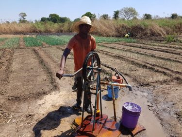 Een man bedient een handwaterpomp in Malawi.