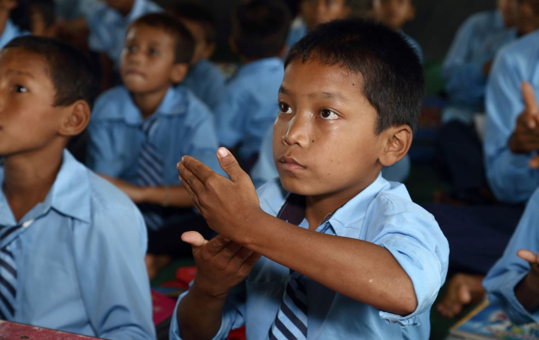 Een jongetje krijgt les in gebarentaal in Nepal.