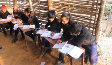 Leerlingen maken huiswerk in een klein klaslokaal in Nepal.