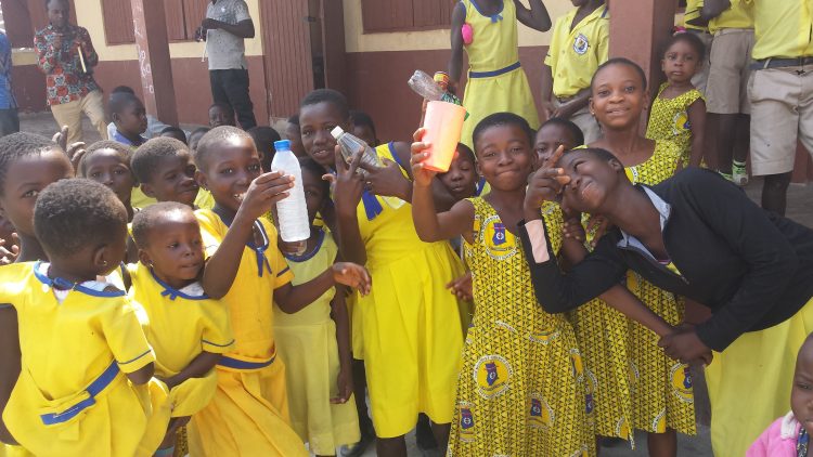 Ghanese kinderen laten hun drinkflesjes zien. 