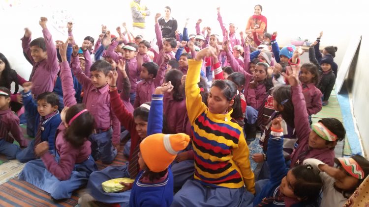 Kinderen steken hun vinger op in de klas in India.