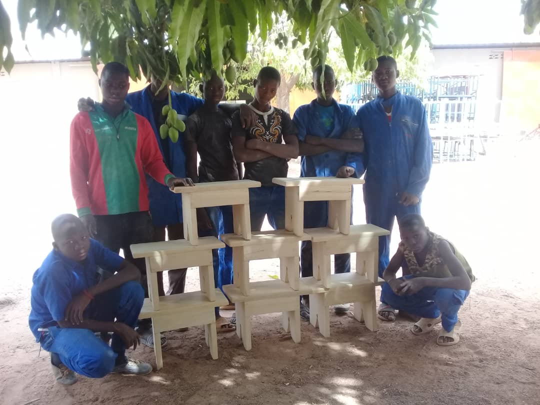 Jongeren bij hun zelfgemaakte houten krukjes